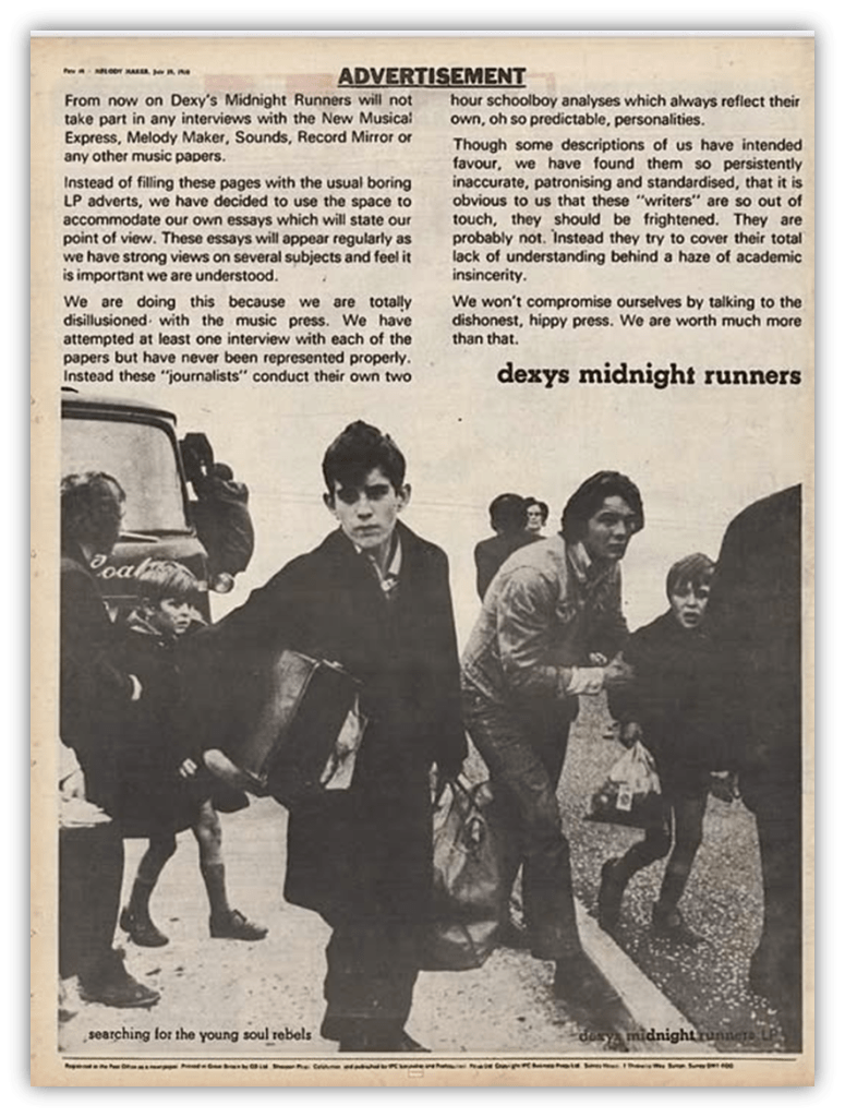 A black-and-white vintage magazine ad for Dexys Midnight Runners shows a group of young men standing and walking outdoors. The group appears serious. Text surrounds the image, describing the band’s perspective on media coverage.