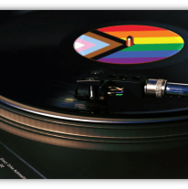 A close-up of a vinyl record spinning on a turntable. The record’s label features the Progress Pride Flag, showing rainbow stripes, chevron, and trans colors. The turntable brand “Technics” is visible in the lower left corner.