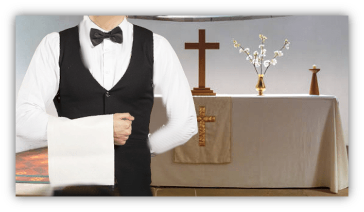 Waiter in a tuxedo at a table set for a religious ceremony, featuring a cross and floral arrangement in the background.
