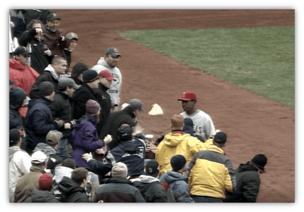 Baseball fans interacting with a player on the field during a game.