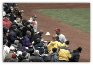 Baseball fans interacting with a player on the field during a game.