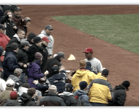 Baseball fans interacting with a player on the field during a game.