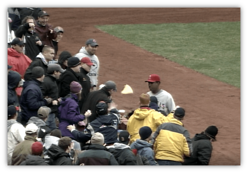Baseball fans interacting with a player on the field during a game.