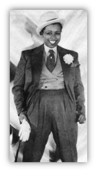 A stylish person in a suit and hat, smiling confidently.