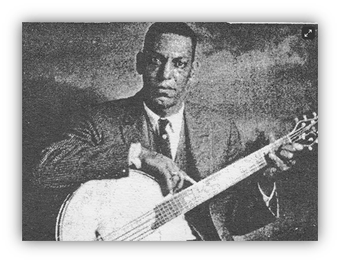 "Historical black and white image of a man playing a guitar, dressed in a suit."