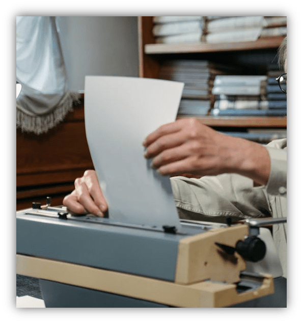 "Person using a typewriter with a blank sheet of paper."