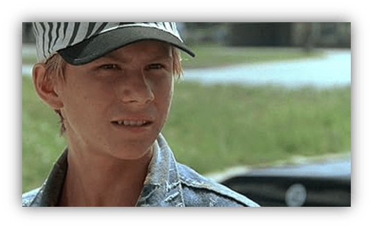 Young boy in a striped cap, looking intently outdoors.
