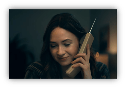 Woman smiling while talking on a vintage telephone.