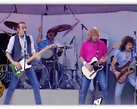"Live Aid performance featuring a rock band on stage with guitars and drums."