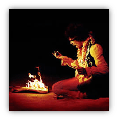 "Musician performing with a burning guitar on stage."