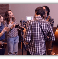 "Group of musicians performing in a studio, featuring guitars and a double bass."