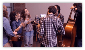 "Group of musicians performing in a studio, featuring guitars and a double bass."