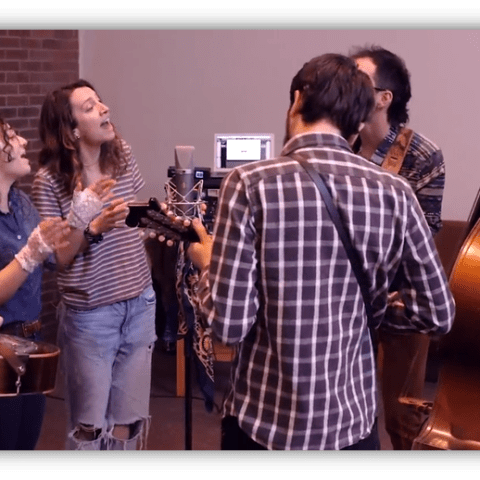 "Group of musicians performing in a studio, featuring guitars and a double bass."