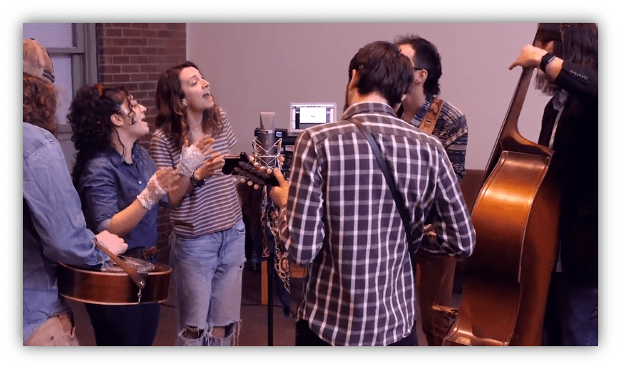 "Group of musicians performing in a studio, featuring guitars and a double bass."