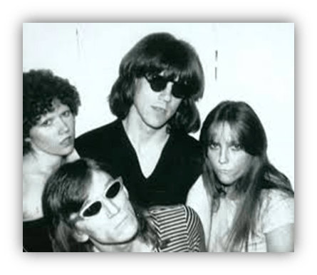 Black and white photo of four people wearing sunglasses, posing together with a playful expression.