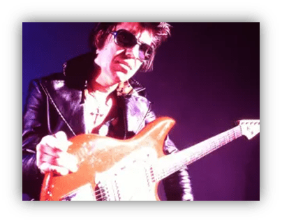 "Rock musician in sunglasses holding an electric guitar on stage."