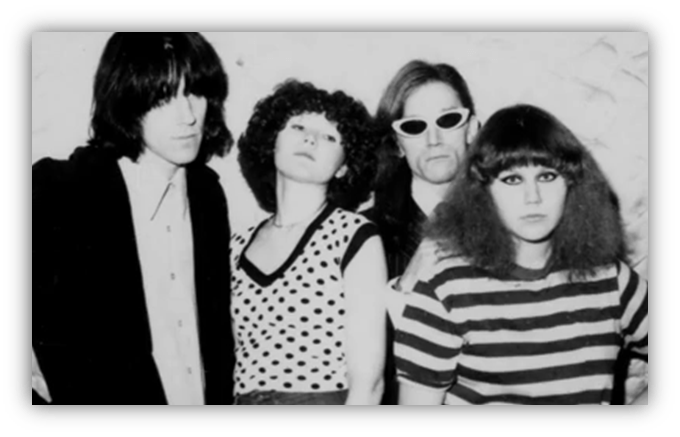 "Black and white photo of a four-member band posing with unique fashion styles."