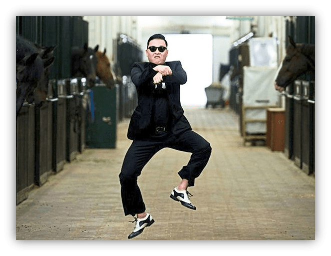 "Man in black suit and sunglasses dancing in a stable with horses."