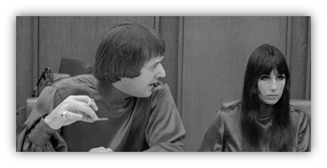 "Black and white image of two people in discussion at a meeting, one gesturing with a pen."