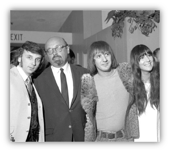 Four people posing together at an event, showcasing 1970s fashion and hairstyles.