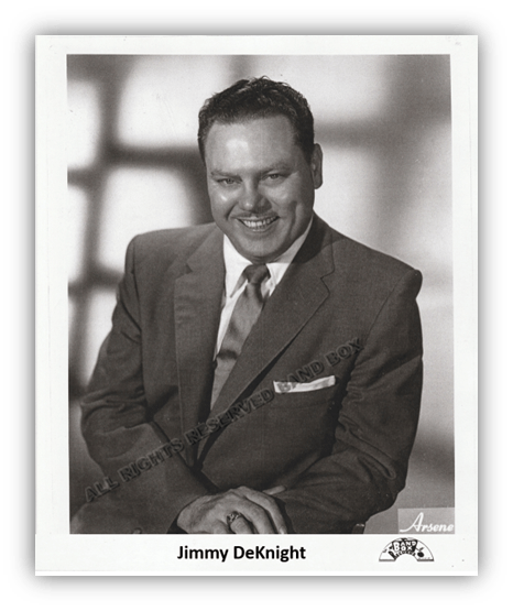 "Black and white portrait of Jimmy DeKnight smiling in a suit."