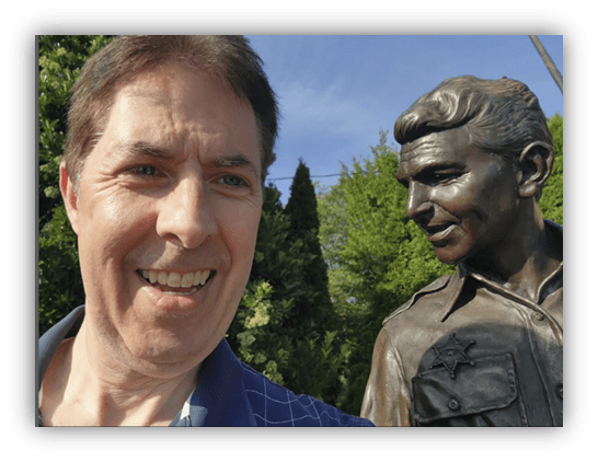 Selfie with a bronze statue in a park.
