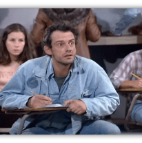Student looking confused in a classroom setting, taking notes.