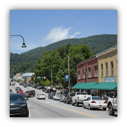 "Scenic street view of a small town with shops and mountains in the background."