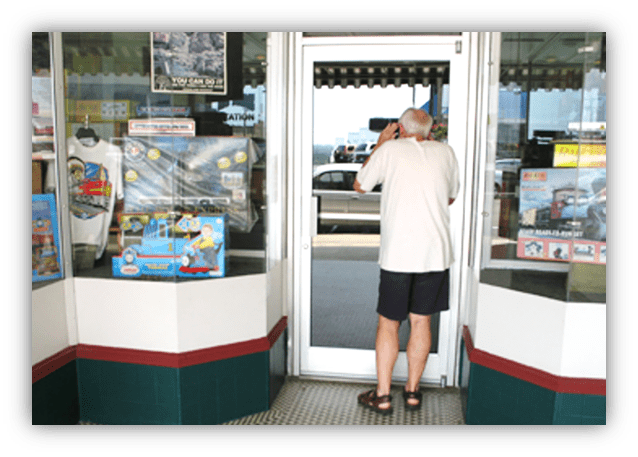 "Older man photographing storefront with souvenirs and merchandise."