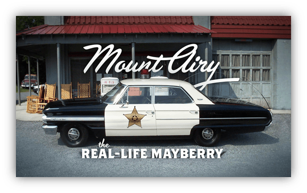 Alt text: "Classic police car in Mount Airy, the real-life Mayberry, with a historic building in the background."