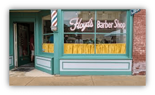 "Exterior view of Floyd's Barber Shop featuring a classic sign and bright yellow curtains."