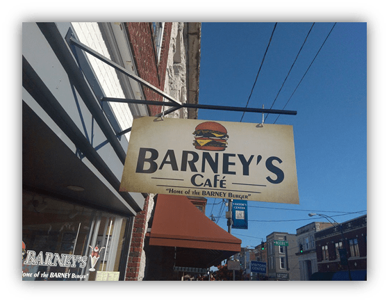 "Barney's Café sign featuring the 'Home of the BARNEY Burger' in a vibrant street setting."