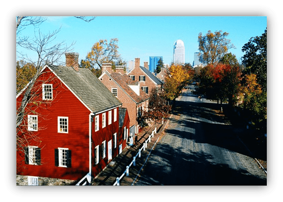 "Historic red houses with autumn foliage and a skyline in the background."