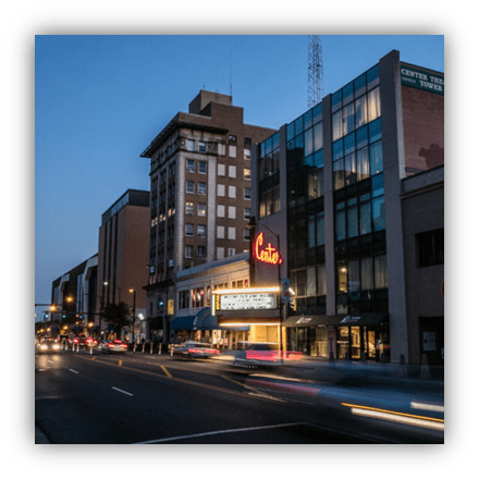 "Downtown street view at dusk featuring the historic Corte Theatre and modern buildings."