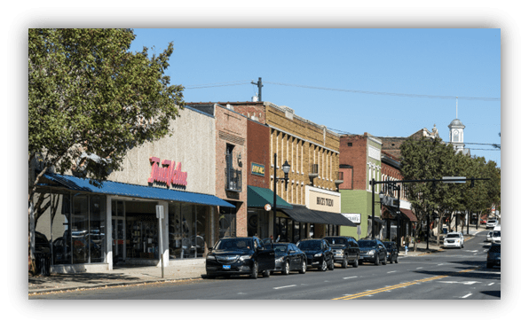 "Main street with shops and parked cars in a small town."