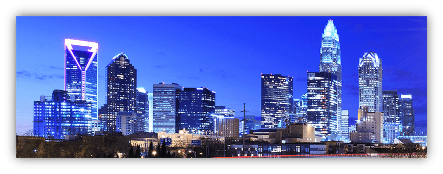 "Charlotte skyline at dusk with illuminated skyscrapers."