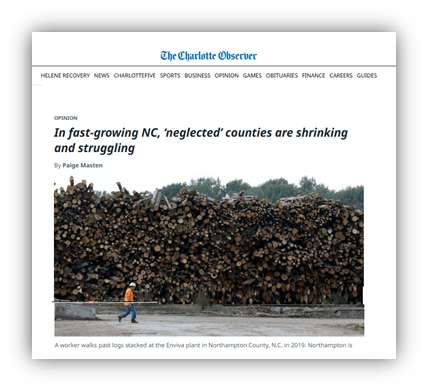 Worker walking past stacked logs at Enviva plant in Northampton County, NC, highlighting local economic challenges.