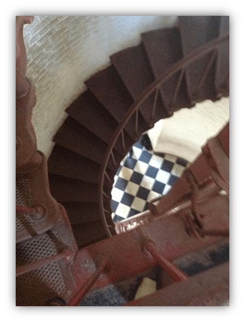 Spiral staircase view with checkered floor below.