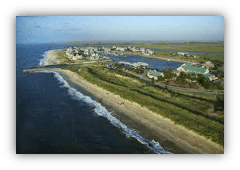 Aerial view of a coastal town with sandy beach and ocean waves.