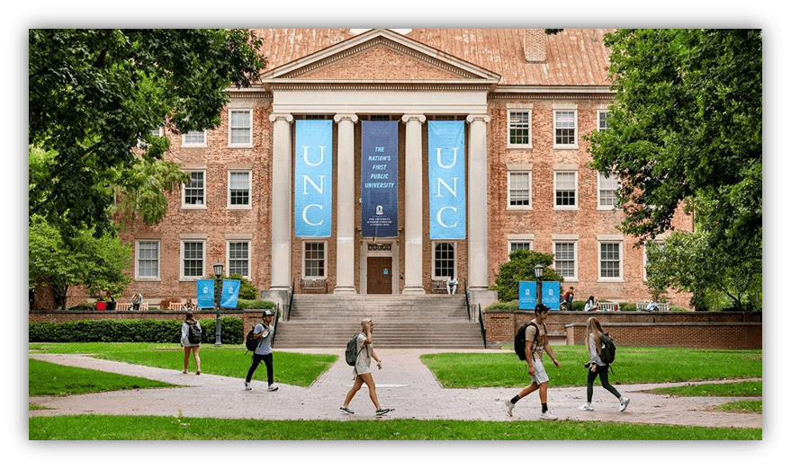 Students walking in front of the University of North Carolina's historic building with banners.