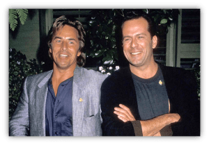 "Two smiling men in stylish outfits posing together outdoors."
