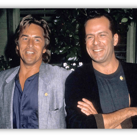 "Two smiling men in stylish outfits posing together outdoors."