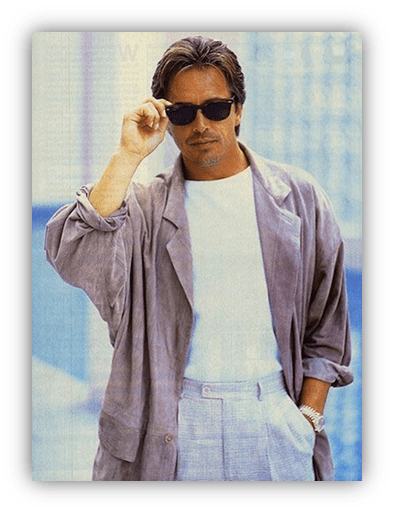 Stylish man in sunglasses and light gray suit, posing confidently.