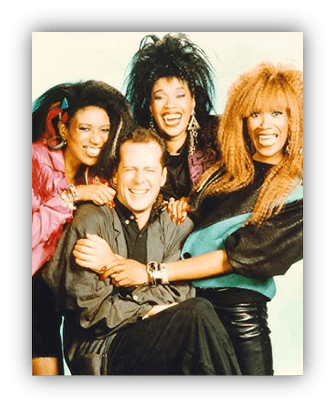 "Group photo of four friends smiling together, featuring vibrant 80s fashion styles."