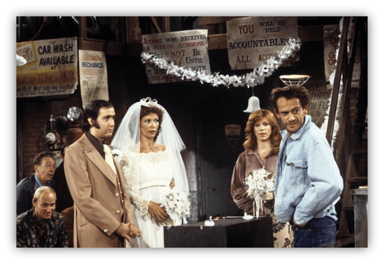 A wedding scene in a vintage sitcom with a bride, groom, and guests in a decorated setting.