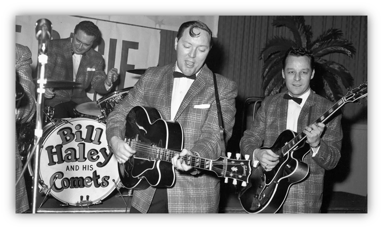 Bill Haley and His Comets performing live, featuring musicians in tuxedos with guitars and a drum set.