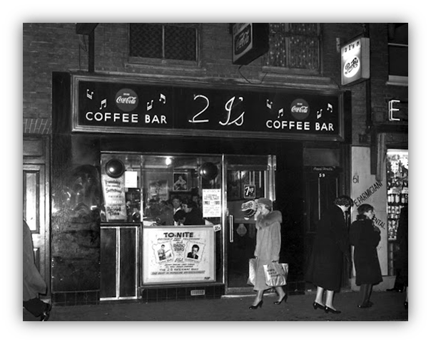 "Historic 2 I's Coffee Bar facade in black and white, featuring vintage signage and pedestrians."