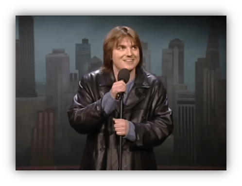 Comedian performing stand-up in a leather jacket on stage.