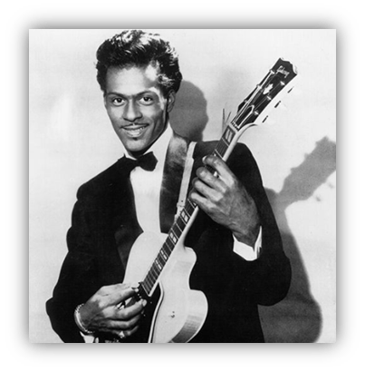 "Black and white portrait of a musician playing guitar, dressed in a tuxedo."