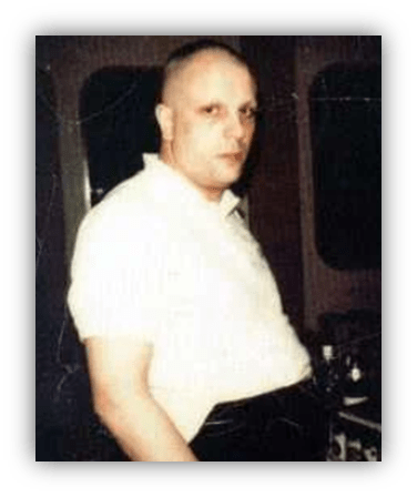 "Vintage portrait of a man in a white shirt, standing indoors."